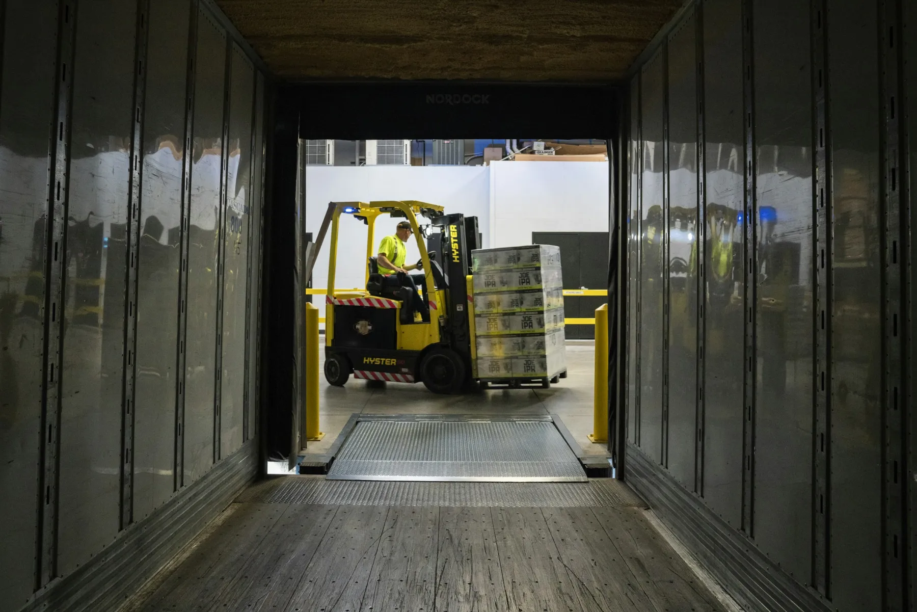 A forklift loading pallets into a trailer at the dock